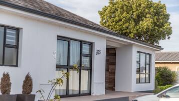 Une maison moderne à deux étages, dotée de grandes fenêtres, portant le numéro 395, et devant laquelle est garée une voiture.