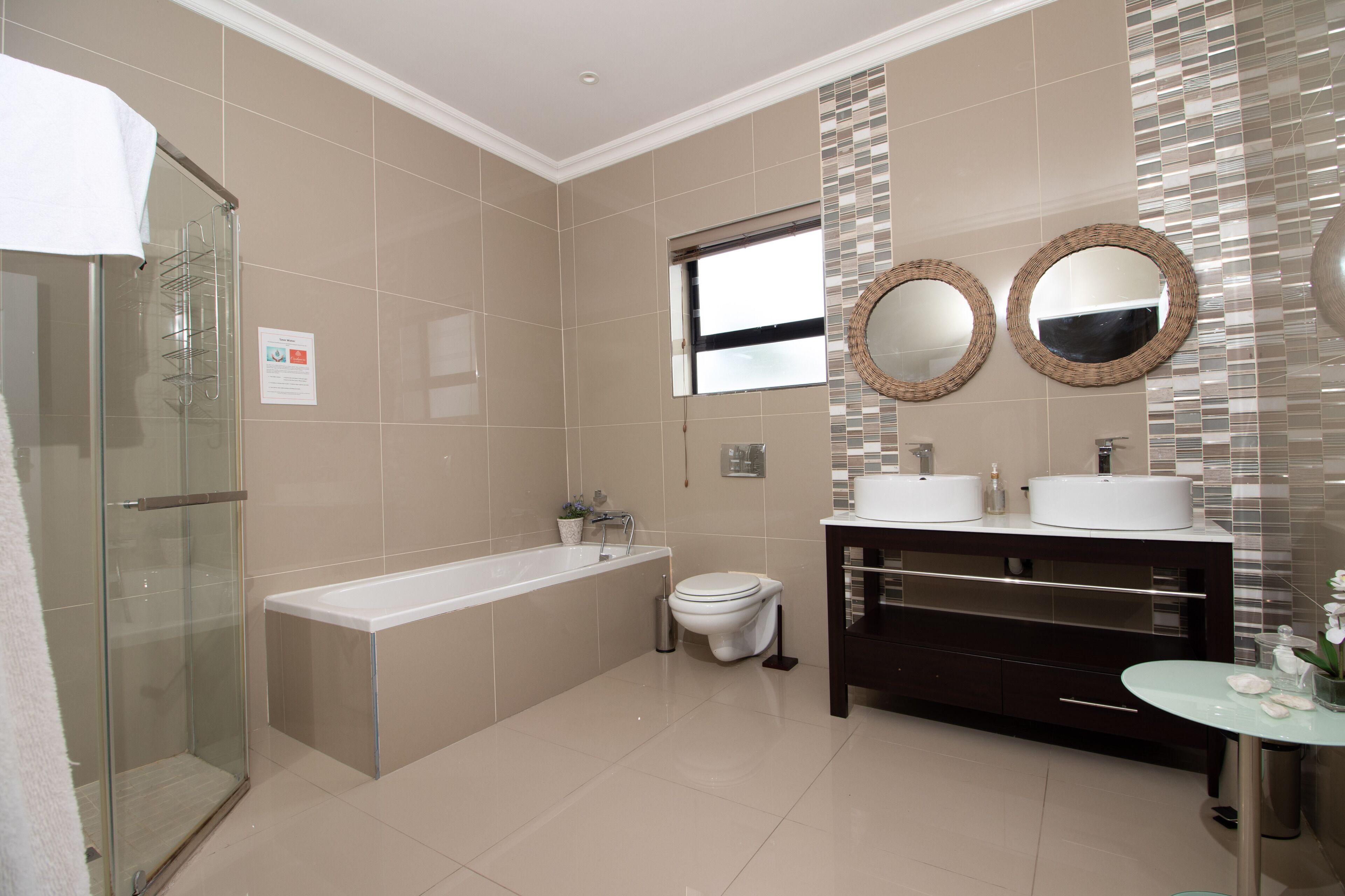 Un baño moderno con cabina de ducha de vidrio, bañera independiente, inodoro y tocador doble.