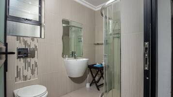 Un baño moderno con inodoro, lavabo y cabina de ducha de vidrio.