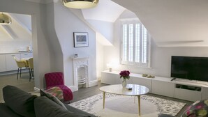 Una sala moderna con un sofá, una mesa redonda de centro, una chimenea y un televisor.