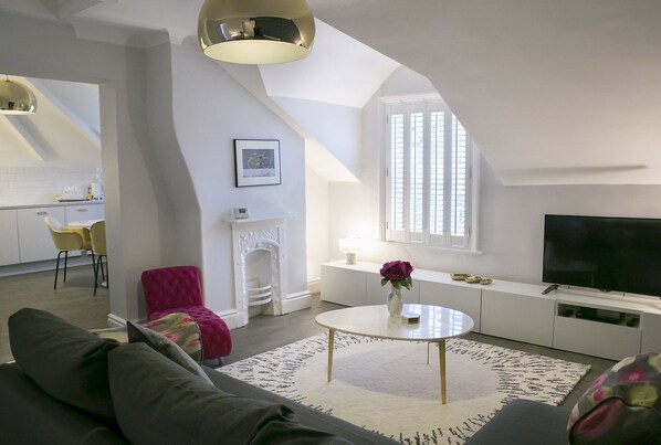 A modern living room with a sofa, a round coffee table, a fireplace, and a television.