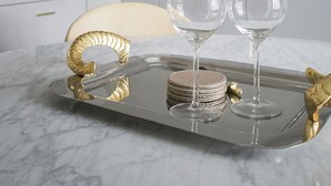 Una cocina moderna con armarios blancos, encimera de mármol y una bandeja con dos vasos y posavasos.