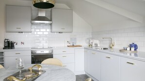 Una cocina moderna con armarios blancos, una isla central y un comedor con mesa de mármol.