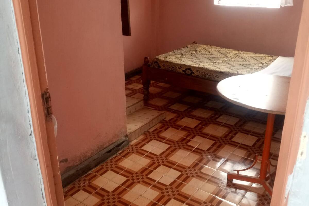 A room with a bed, a small table, and a patterned floor.