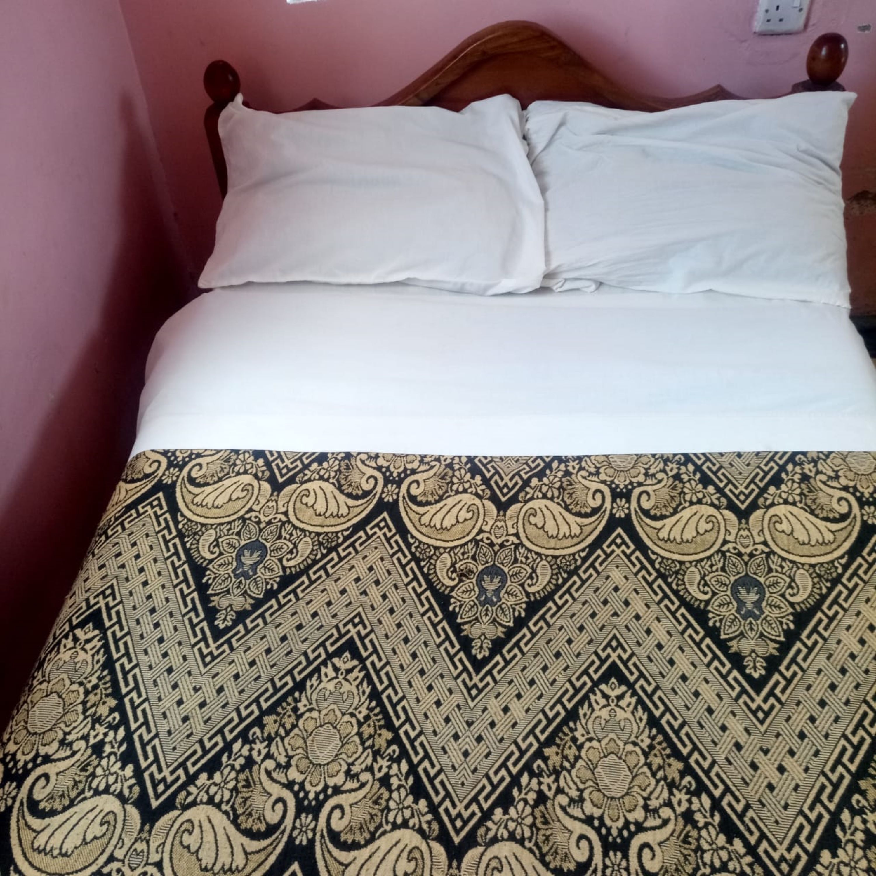 Una cama con ropa blanca y una colcha estampada.