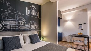 Een moderne hotelkamer met een groot bed, een zithoek met een tafel en stoelen, en een muur met een muurschildering over bouw.'