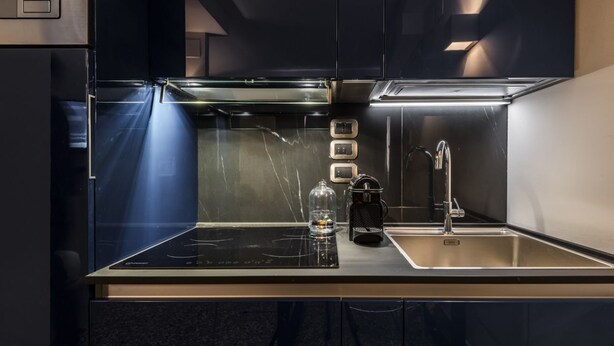 Een moderne keuken met een zwart aanrecht, roestvrijstalen apparatuur en een spoelbak.
