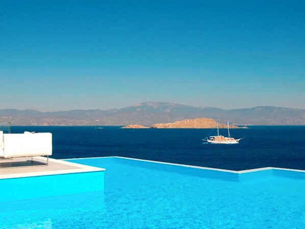 Ein klares, blaues Infinity-Pool mit Blick auf das Meer und ferne Berge.
