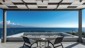 A modern outdoor seating area with a view of the sea and distant mountains. - Welcome to Villa Soligia! Beach Front Villa Large Private Pool Amazing Sea View (Corinth)