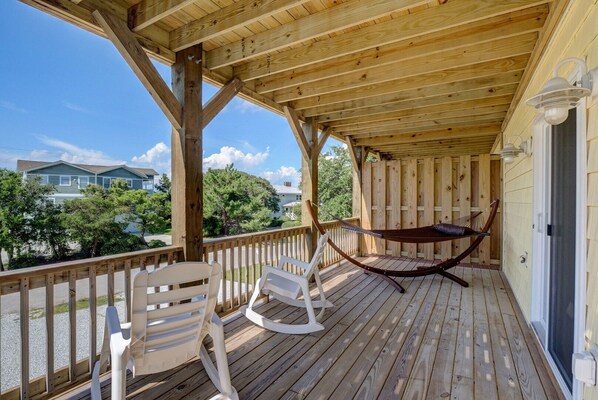 A wooden deck with a hammock, white chairs, and a view of houses and trees. - Island Oasis, Elevator, Beautiful Decor (Topsail Beach)