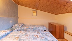 Un dormitorio con dos camas, techo de madera, un pequeño espejo y un armario de madera.