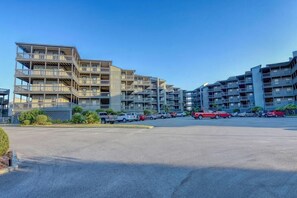 A multi-story residential building with balconies, a parking lot, and a clear sky. - Oceanfront Condo with amazing views of The Atlantic (North Topsail Beach)