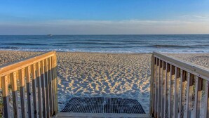 A wooden boardwalk leading to a sandy beach with a view of the ocean and a distant boat. - Oceanfront Condo with amazing views of The Atlantic (North Topsail Beach)