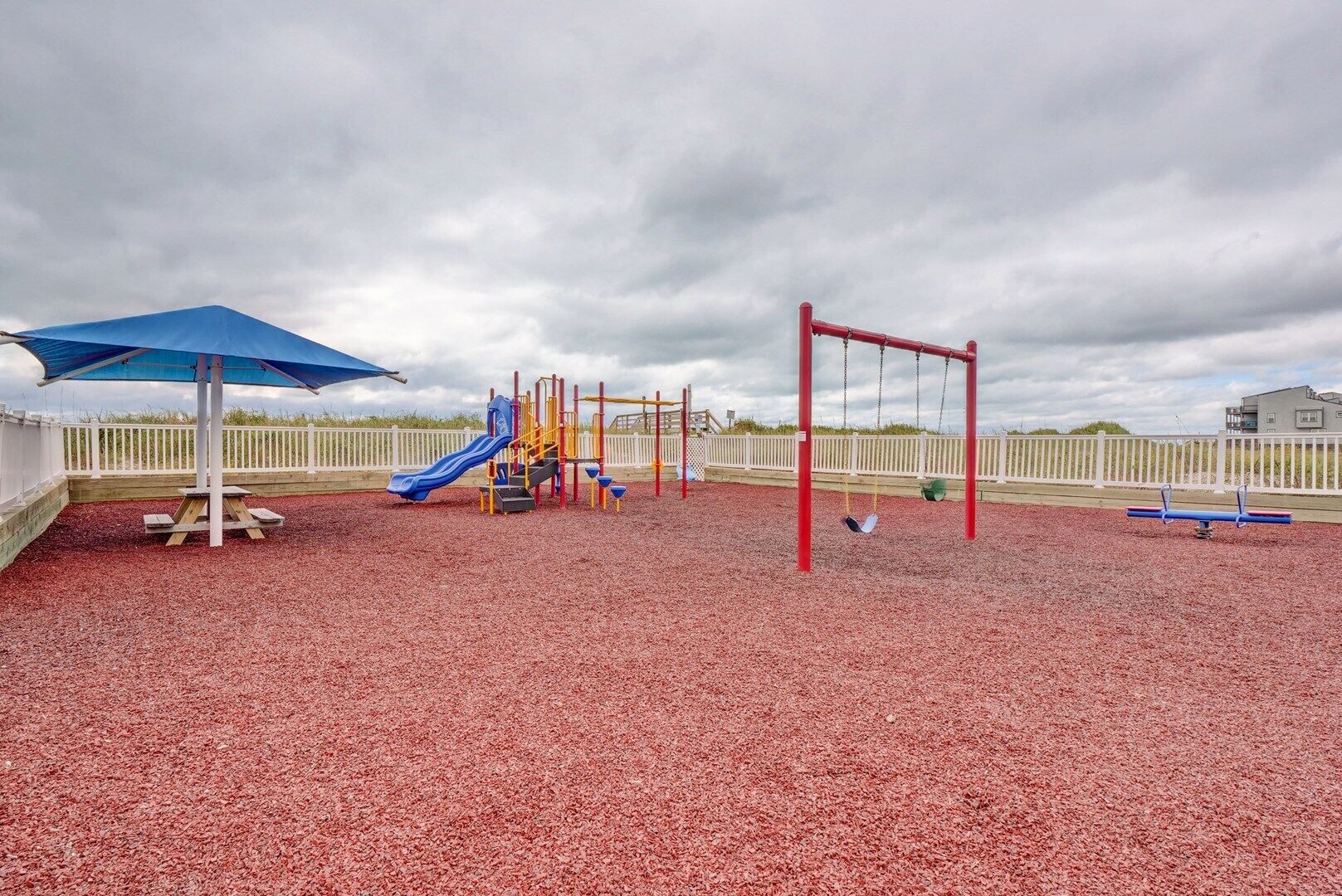 Un parque infantil con tobogán, columpios y una estructura para escalar.
