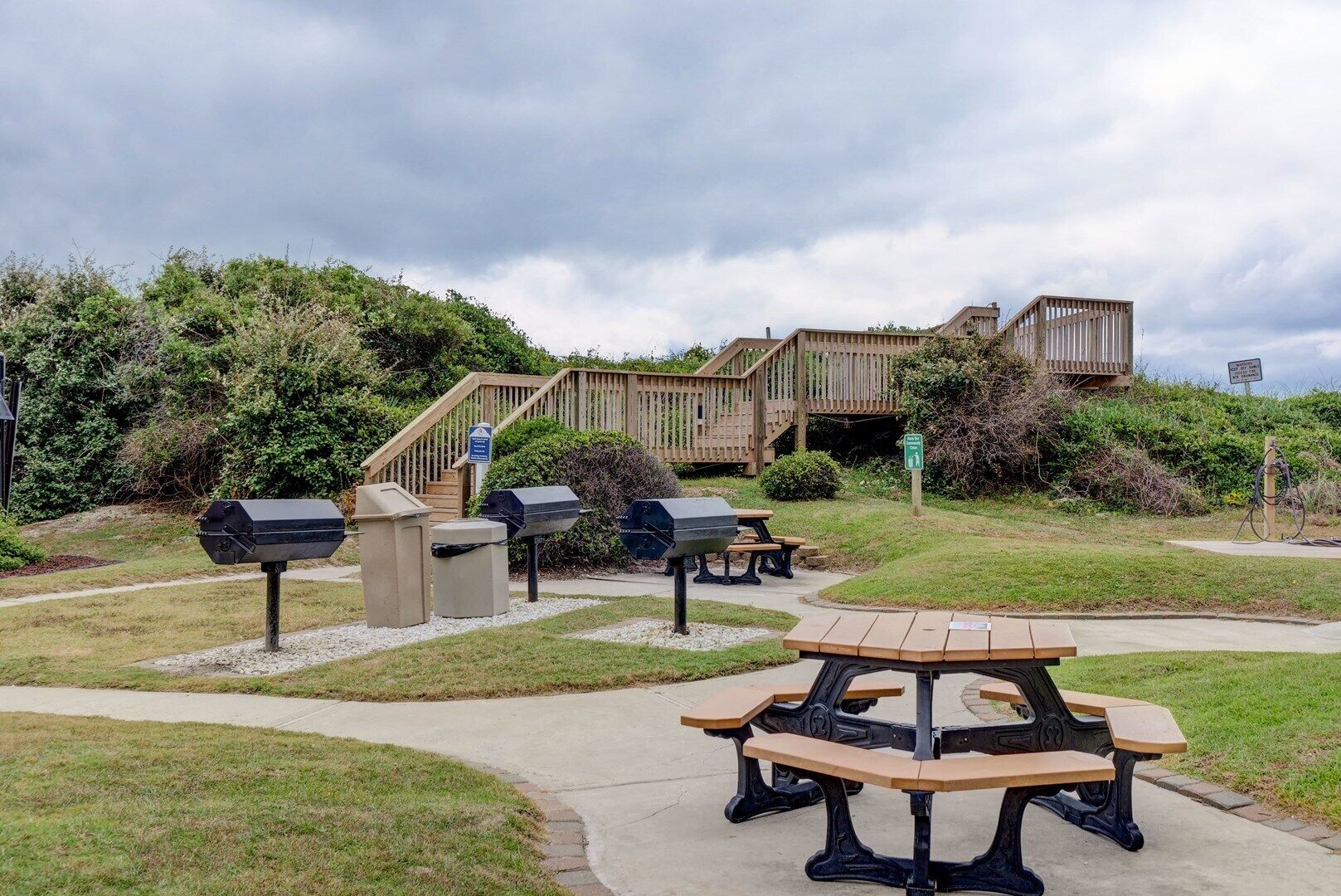 A picnic area with grills, benches, and a wooden deck.