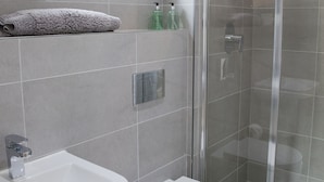 A modern bathroom with a shower, sink, and toilet.
