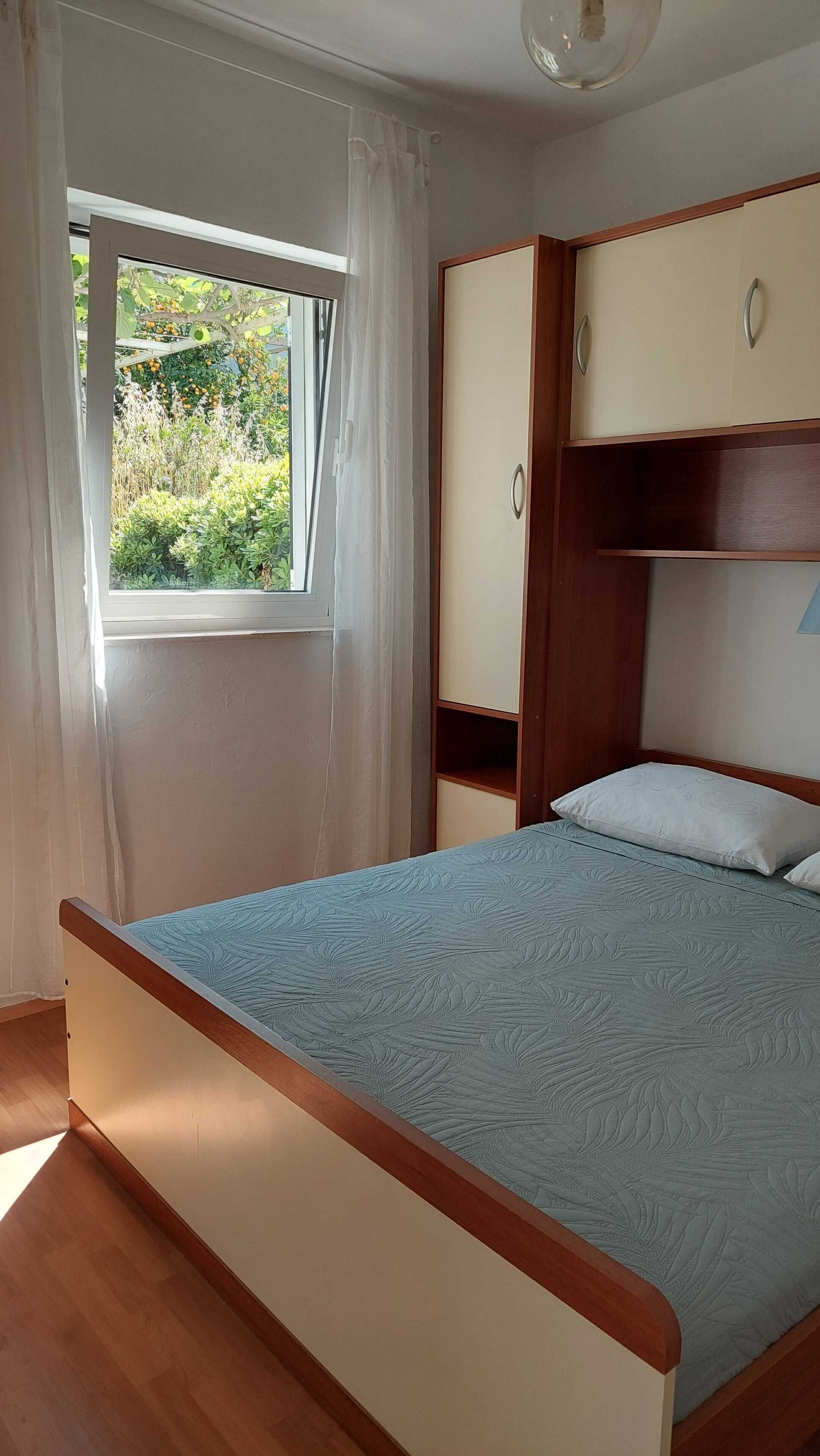 A bedroom with a bed, a window with curtains, a wardrobe, and a ceiling fan.