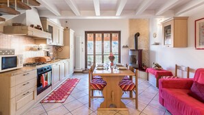 A kitchen with a dining area, wooden staircase, and a red sofa. - Holiday Apartment "Rosalba" At the Foot of Monte Baldo with Balcony and Views (Ferrara Monte Baldo)
