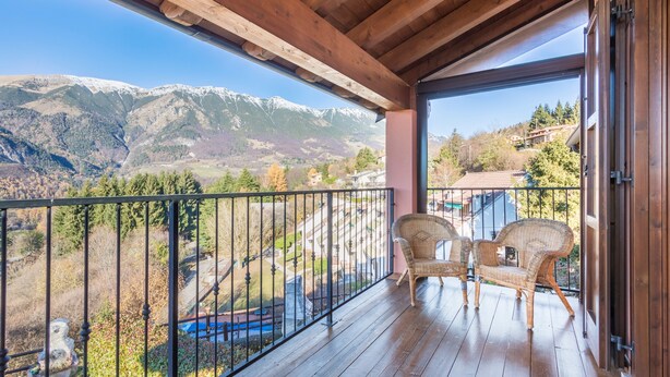 A wooden balcony with two wicker chairs, a view of mountains, and a clear sky. - Holiday Apartment "Rosalba" At the Foot of Monte Baldo with Balcony and Views (Ferrara Monte Baldo)