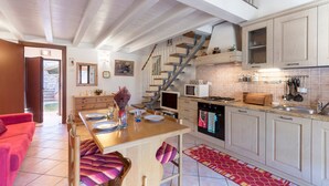 A modern kitchen with a dining area, a staircase, and a red carpet. - Holiday Apartment "Rosalba" At the Foot of Monte Baldo with Balcony and Views (Ferrara Monte Baldo)