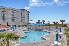 Un hôtel doté d’une piscine, de chaises longues et de palmiers.
