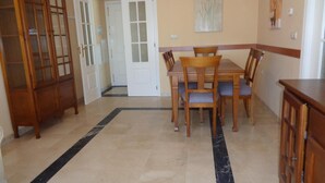 Un coin repas avec une table et des chaises en bois, un buffet et une porte donnant sur une autre pièce.