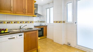 Une cuisine compacte avec des meubles en bois, un lave-vaisselle Siemens, un pare-éclaboussures carrelé et une fenêtre offrant une vue agréable.
