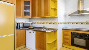 Une cuisine de taille réduite, dotée de meubles en bois, d’un lave-vaisselle, d’un four à micro-ondes et d’une cuisinière.