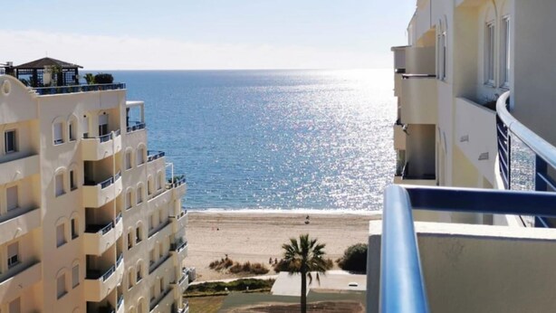 Un hôtel situé sur la côte, doté de balcons offrant une vue sur la plage et la mer.