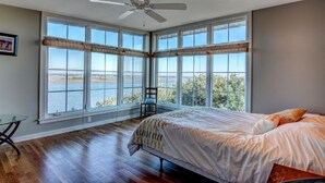 A bedroom with a large window, a bed, a chair, and a ceiling fan. - Soundfront Home with Old World Charm! Claw foot tub, private dock (Topsail Beach)