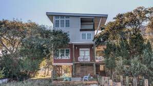 A two-story house with a deck, surrounded by trees and a wooden fence. - Soundfront Home with Old World Charm! Claw foot tub, private dock (Topsail Beach)