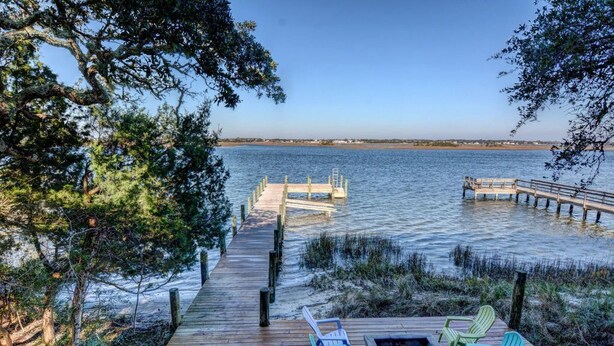 A wooden dock extending into calm waters, surrounded by trees and a clear sky. - Soundfront Home with Old World Charm! Claw foot tub, private dock (Topsail Beach)