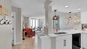 Een moderne keuken met witte kasten, een ingebouwde vaatwasser en een groot eiland met een spoelbak.