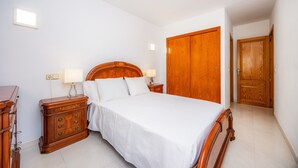 Une chambre à coucher avec un lit en bois, des tables de chevet, une armoire et une petite table de nuit.