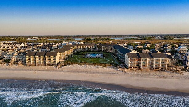 A coastal resort with beachfront villas, a swimming pool, and a beach. - Oceanfront Condo, Steps Away from the beach access (Surf City)