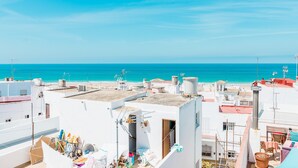 Un edificio costero con varios balcones, vistas despejadas al mar y una terraza con diversos objetos.