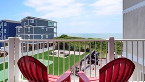 A balcony with red chairs, a view of the sea, and a construction site in the background. - Spectacular Oceanfront Escape, Steps to Beach, Pool, and more (North Topsail Beach)