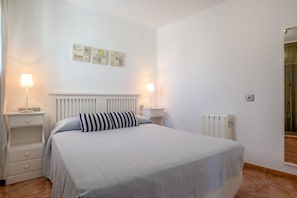 Une chambre à coucher comprenant un lit, deux tables de chevet, un radiateur et des appliques murales.