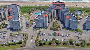 Un complejo hotelero con varias construcciones, una piscina central y vistas a la playa.