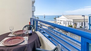 A balcony with a table set for two, overlooking a coastal view with a bridge and buildings. - Apartamento en Marbella con vistas laterales al mar 328 (Marbella)