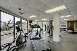 Une salle de sport équipée de tapis de course, de vélos elliptiques et de matériel de musculation.