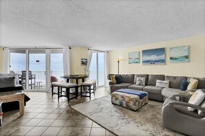 A living room with a sofa, ottoman, and a dining area with chairs and a table. - Top Floor, eagle eye views of The Atlantic! Tons of amenities (North Topsail Beach)