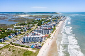 A coastal hotel with multiple buildings, a beach, and a view of the ocean.