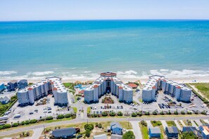 A coastal hotel complex with multiple buildings, a central pool, and a beach view.