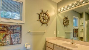 Un bagno con uno specchio grande, una decorazione a forma di timone e un porta asciugamani.