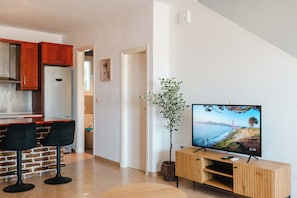 Moderni keittiö, jossa on jääkaappi, puukalusteet ja ruokailutila, jossa on kaksi mustaa tuolia.