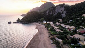 Zona costera con playa, casas y montaña.