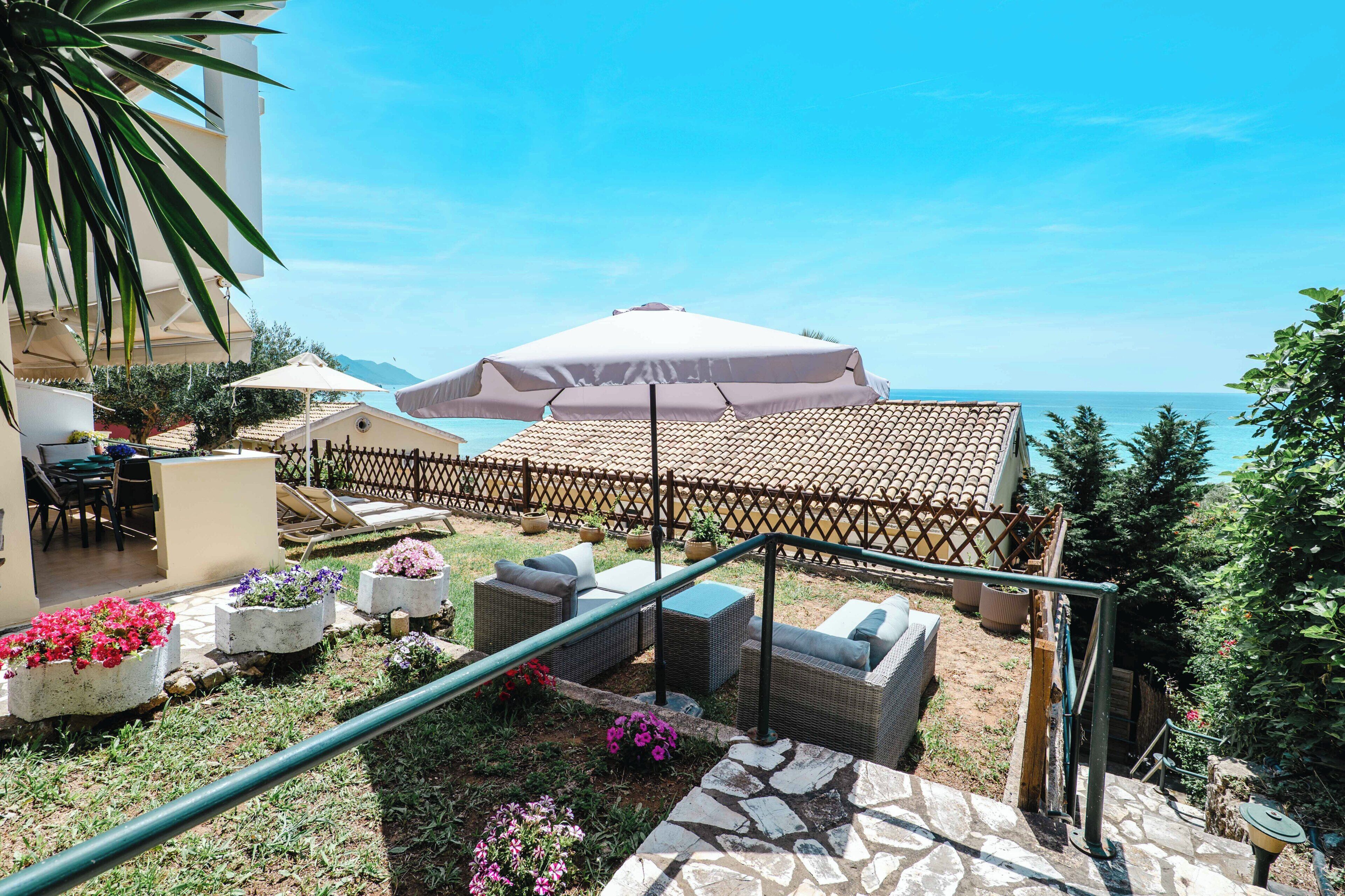 Un patio con mobiliario exterior, una pérgola con toldo y vistas al mar.