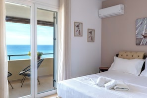Ett hotellrum med en säng, en balkong med utsikt över havet och en luftkonditioneringsanläggning på väggen.