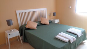 A neatly made bed with green bedding and two pillows, a bedside lamp, and a folded towel on the nightstand. - Apartamento en Marbella con vistas laterales al mar 332 (Marbella)